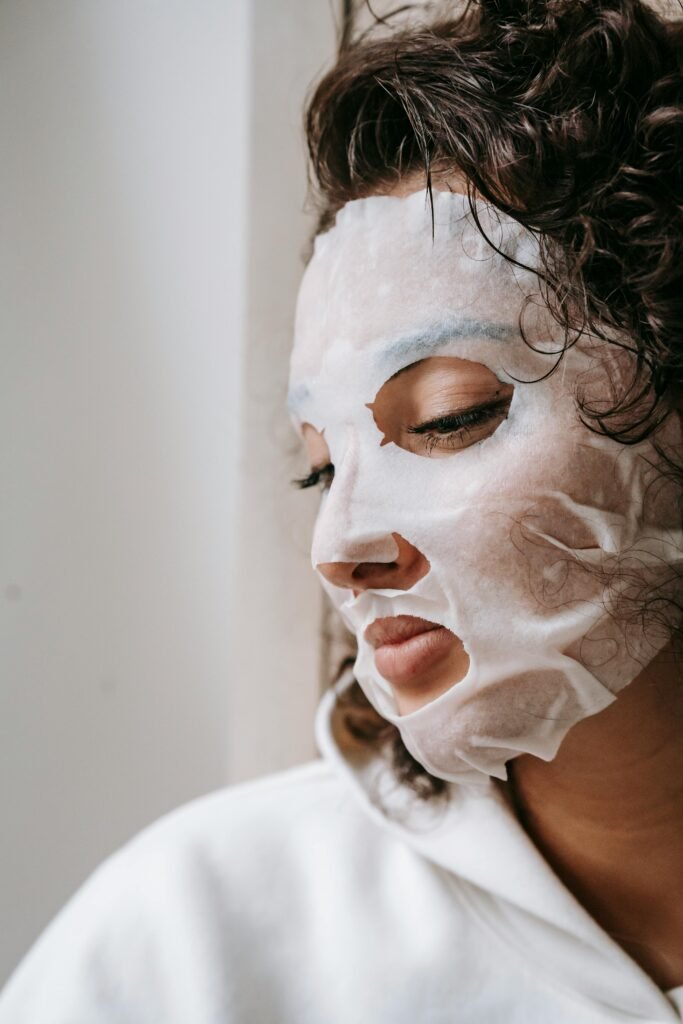 Side view of crop concentrated female with dark hair in facial mask looking down during daily skincare routine at home